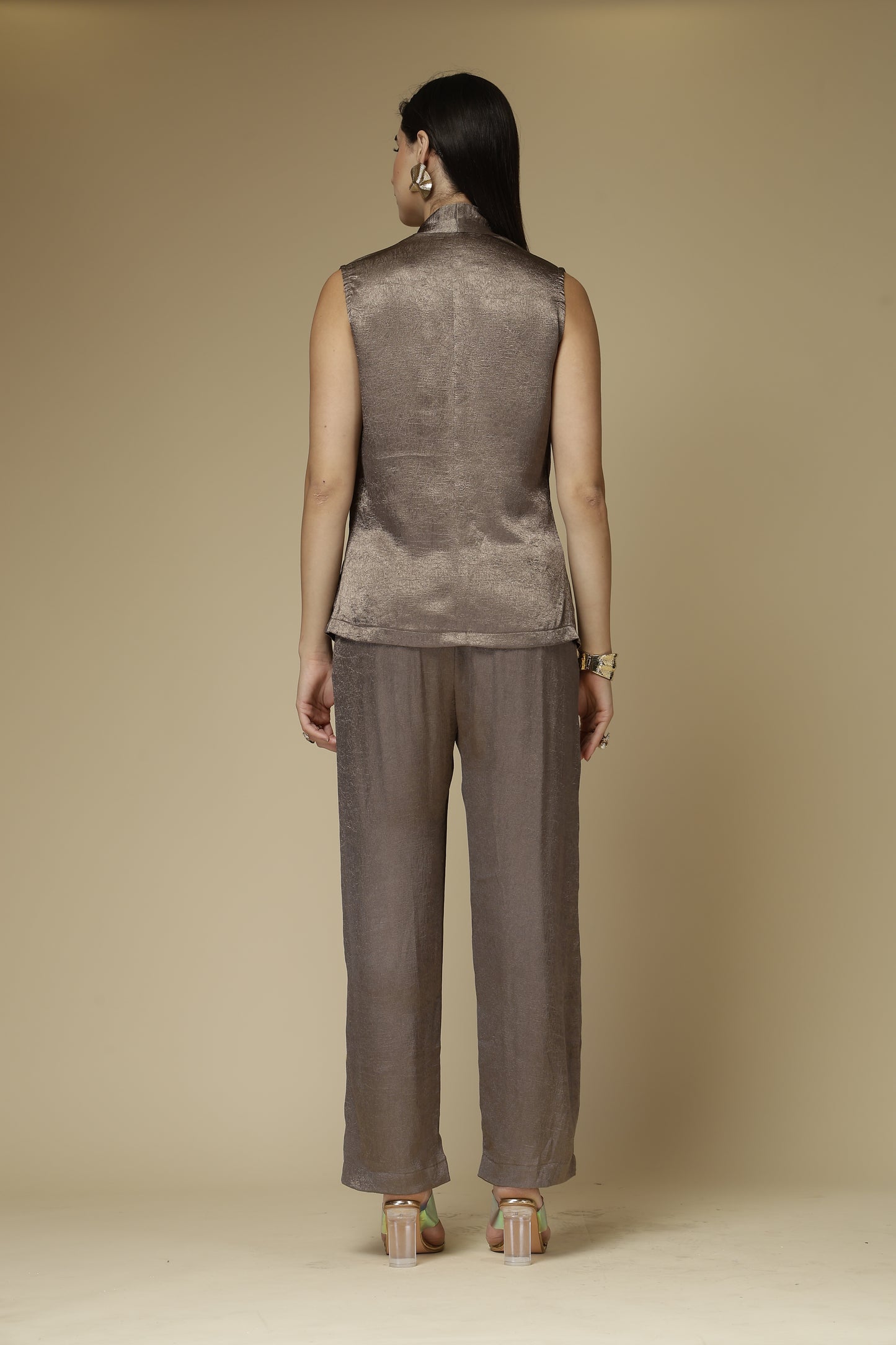 Woman wearing a brown sleeveless top and pants against a beige background