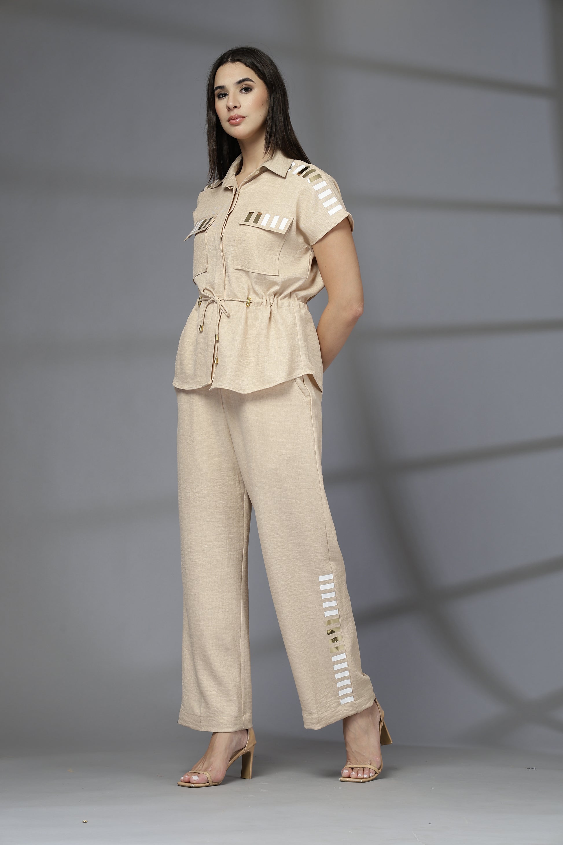 Woman wearing a beige outfit with white accents against a gray background