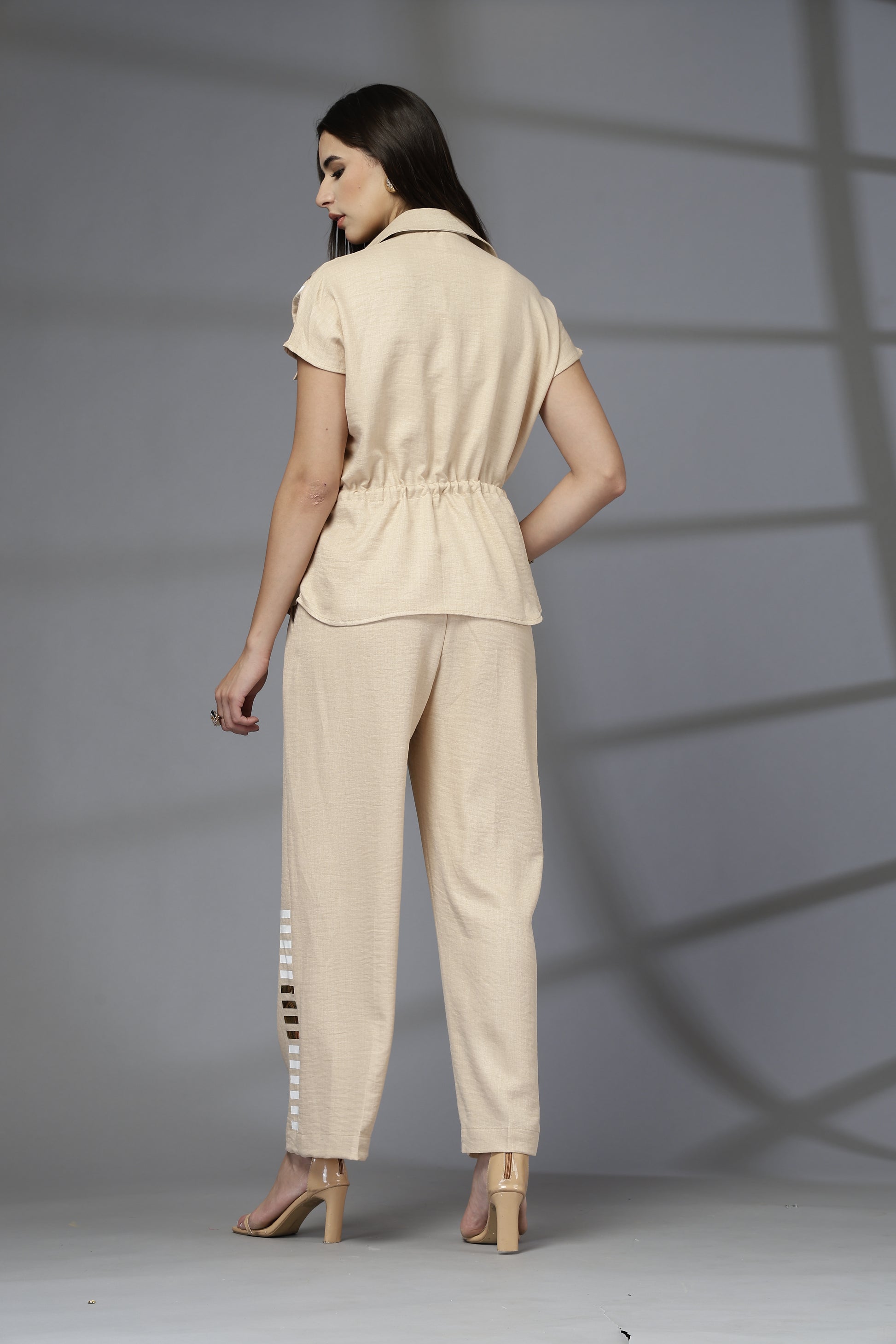 Woman wearing a beige outfit standing against a gray background