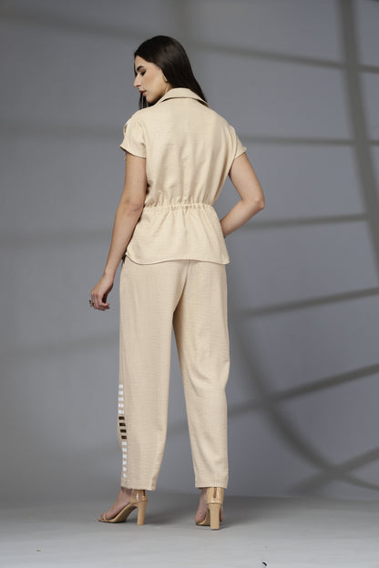 Woman wearing a beige outfit standing against a gray background