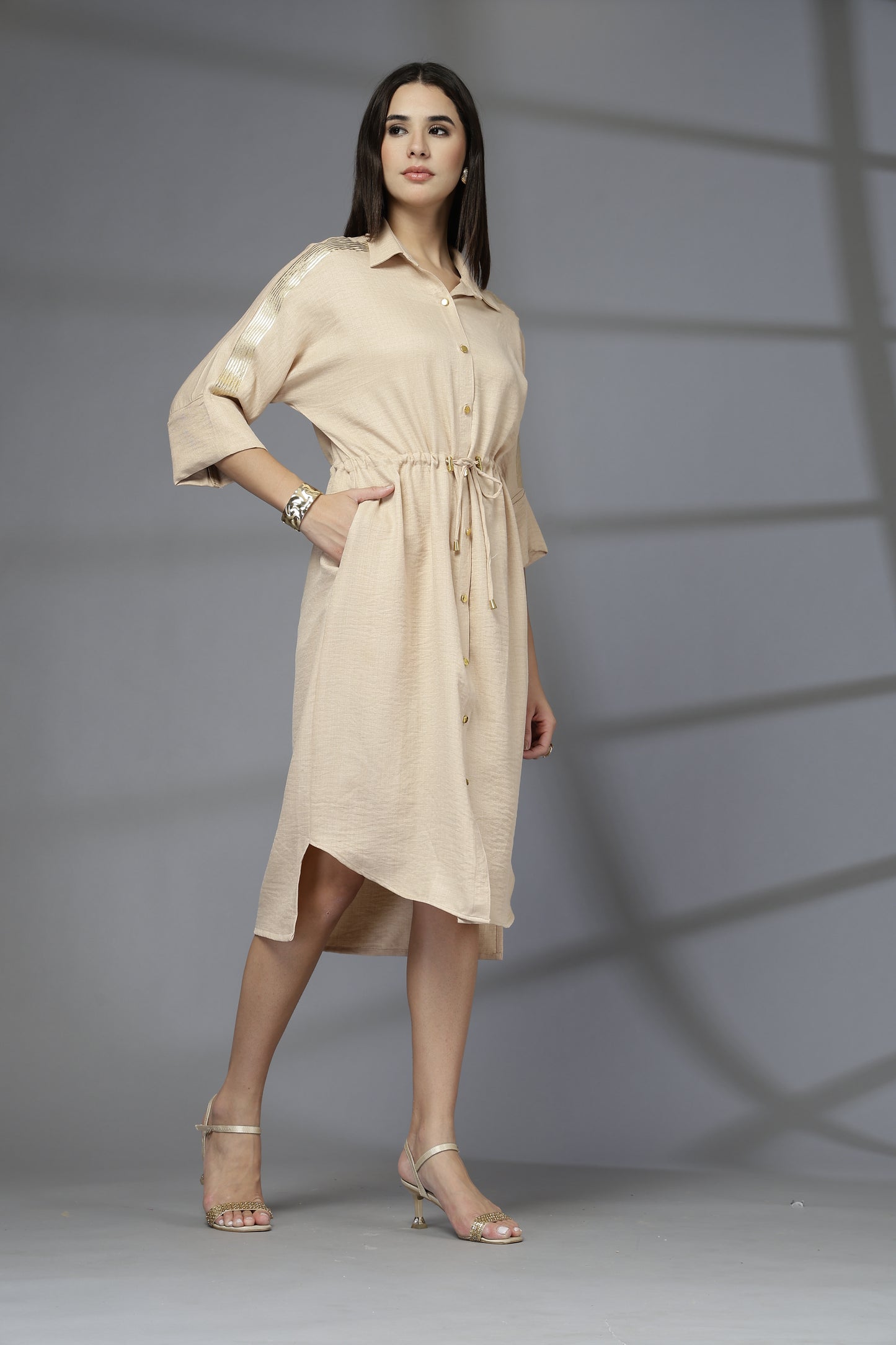 Woman wearing a beige dress against a gray background