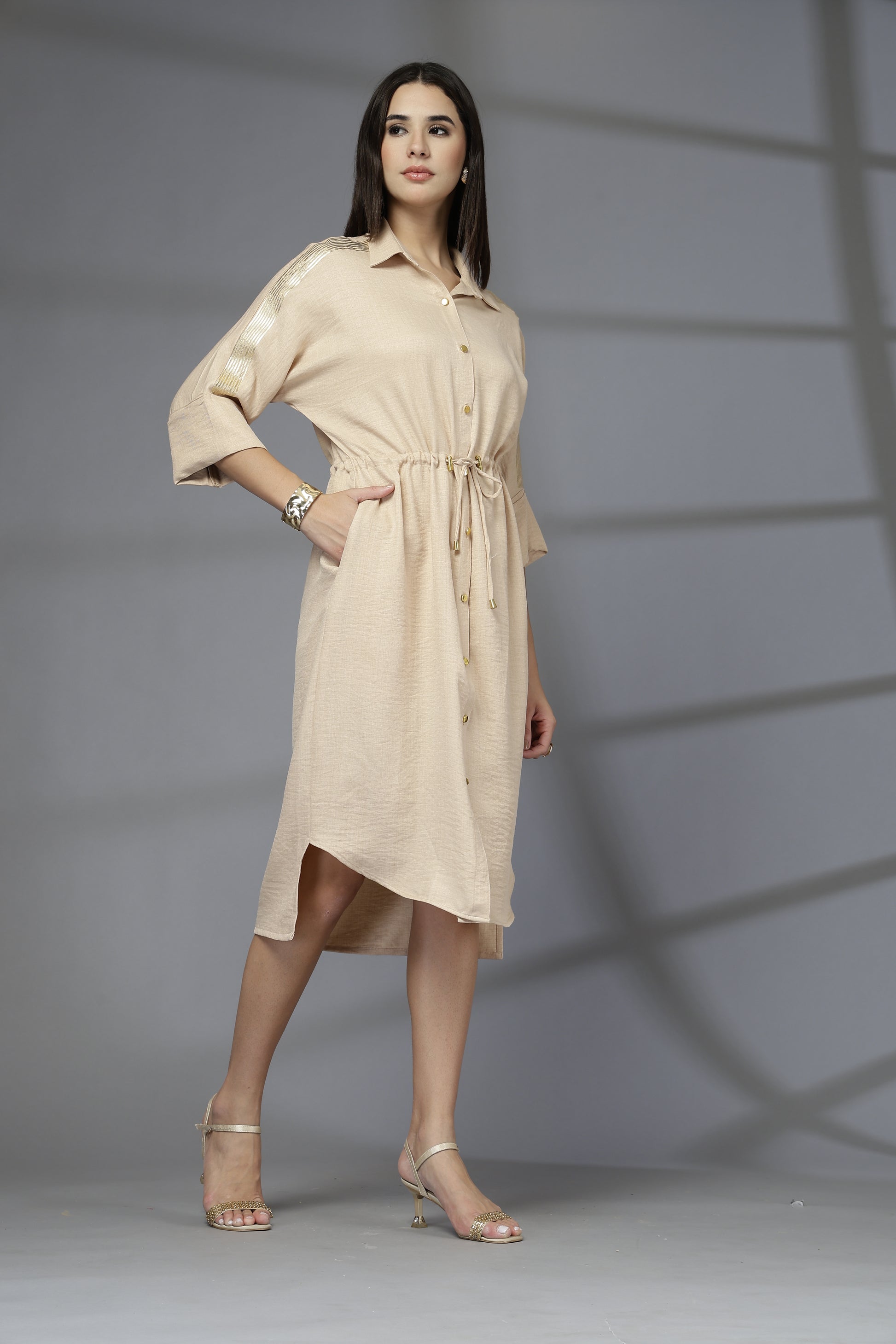 Woman wearing a beige dress against a gray background
