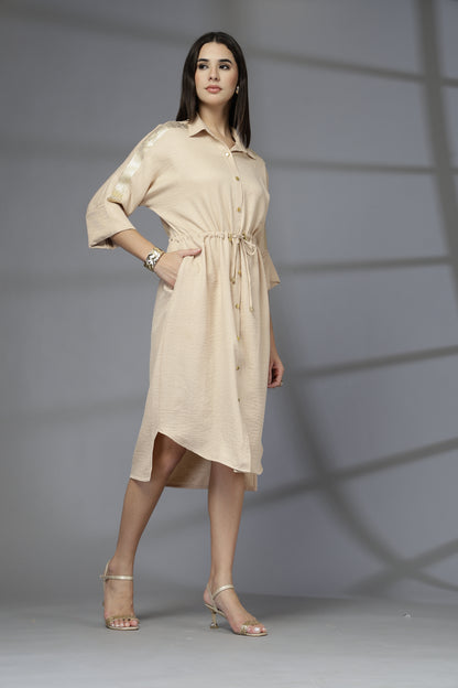 Woman wearing a beige dress against a gray background