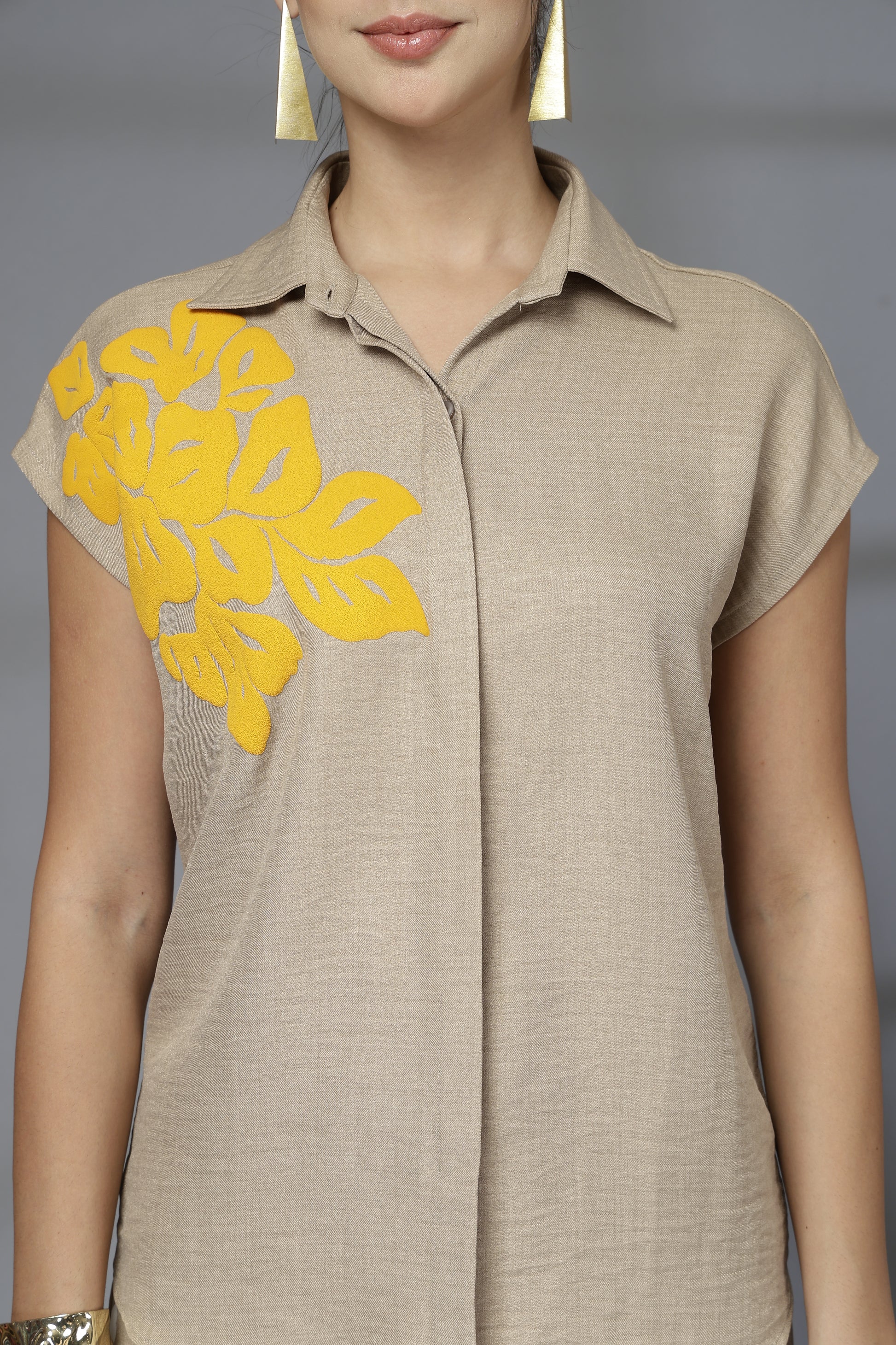Beige dress with yellow floral details on a plain background