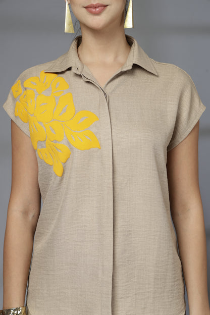 Beige dress with yellow floral details on a plain background