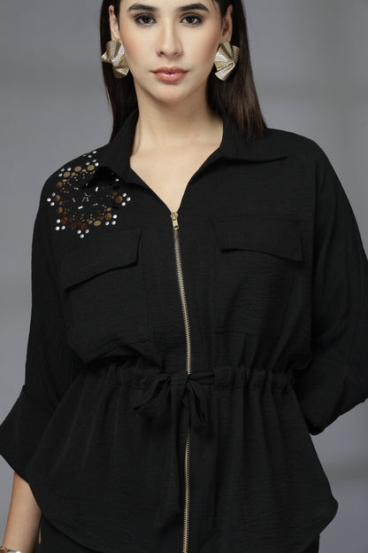 Woman wearing a black outfit with decorative elements on a gray background
