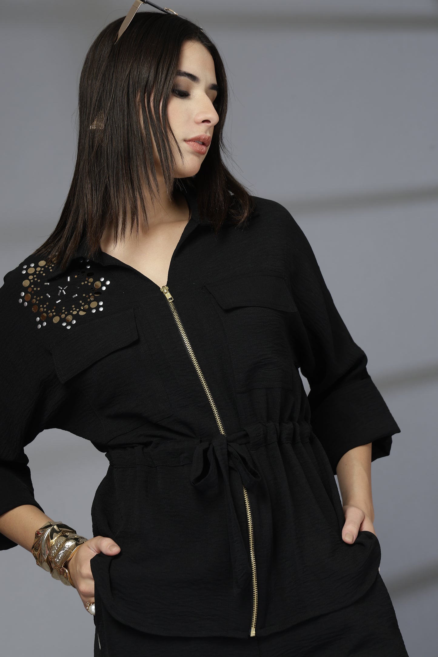Woman wearing a black outfit with decorative elements on a gray background