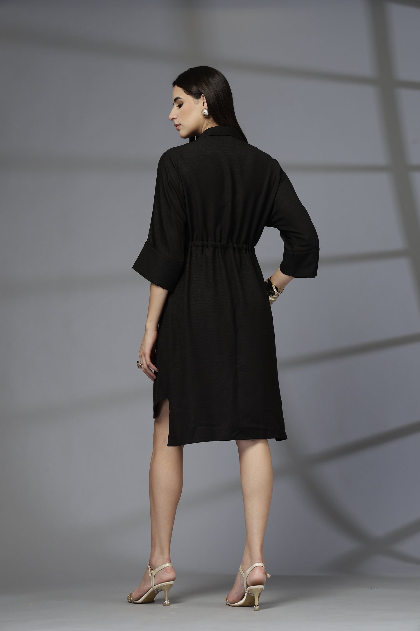 Woman wearing a black dress against a gray background
