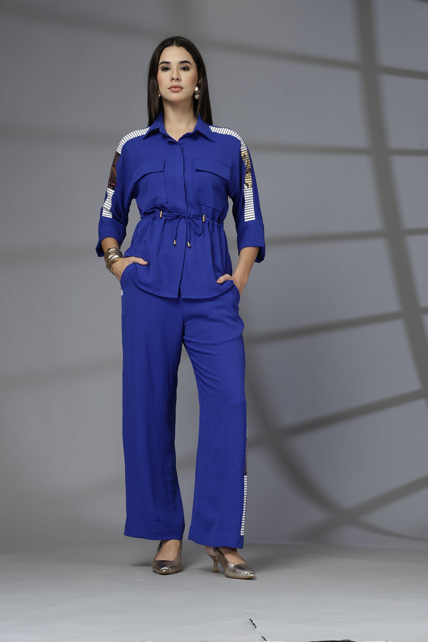 Woman wearing a blue jumpsuit with white accents against a gray background