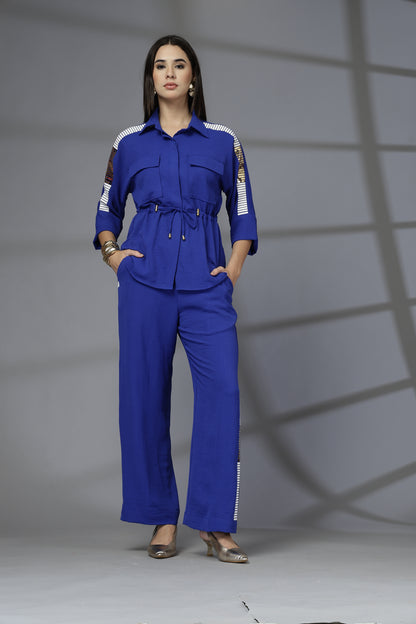 Woman wearing a blue jumpsuit with white accents against a gray background
