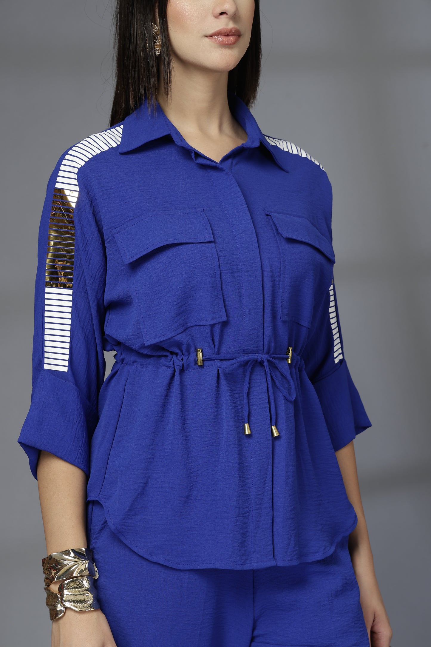 Woman wearing a blue outfit with white accents on a gray background