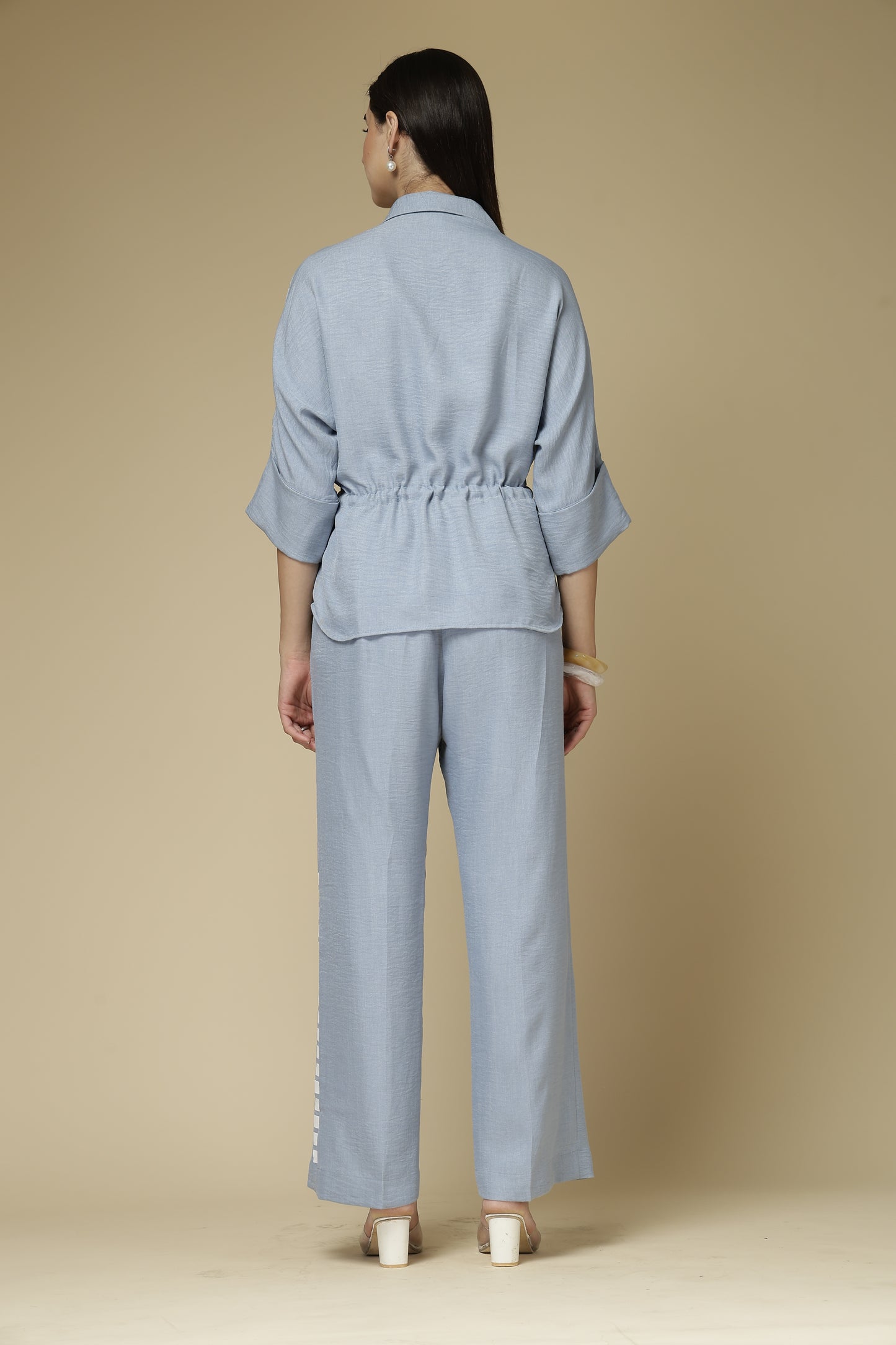 Woman wearing a light blue outfit on a beige background