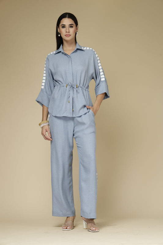 Woman wearing a light blue outfit with a matching jacket and pants on a beige background