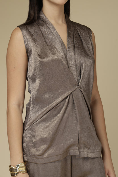 Woman wearing a brown sleeveless top with a draped design on a beige background