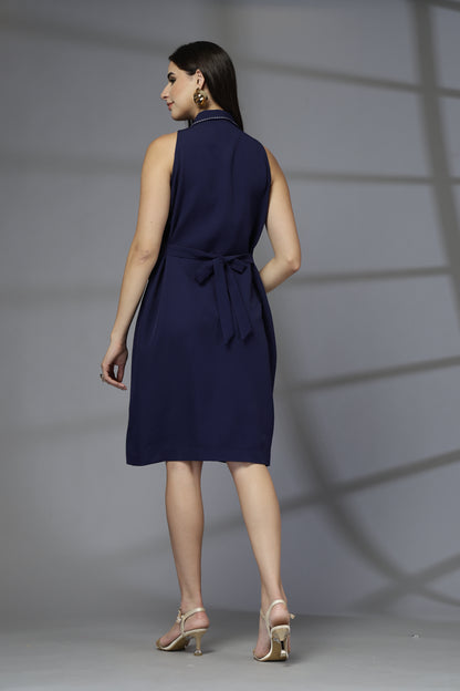 Woman wearing a navy blue sleeveless dress against a gray background