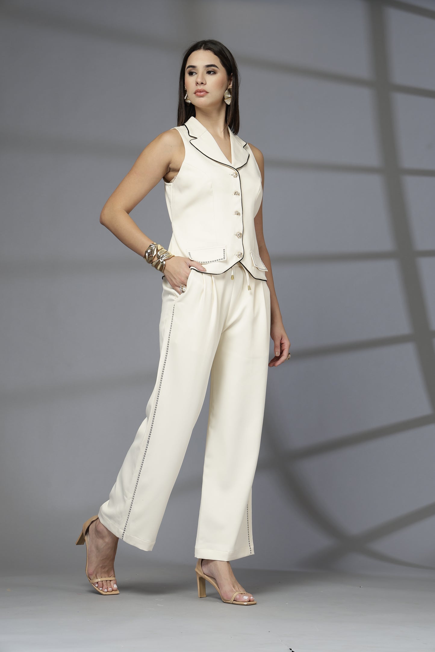 Woman in a white outfit standing against a gray background