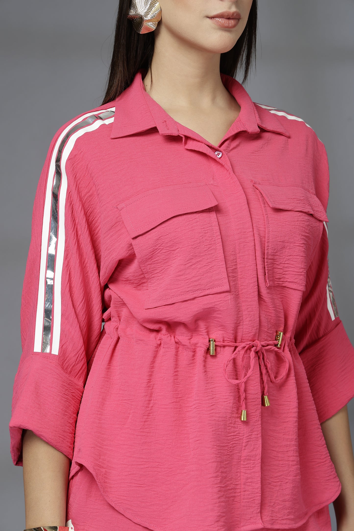 Pink outfit with white stripes on sleeves against a gray background