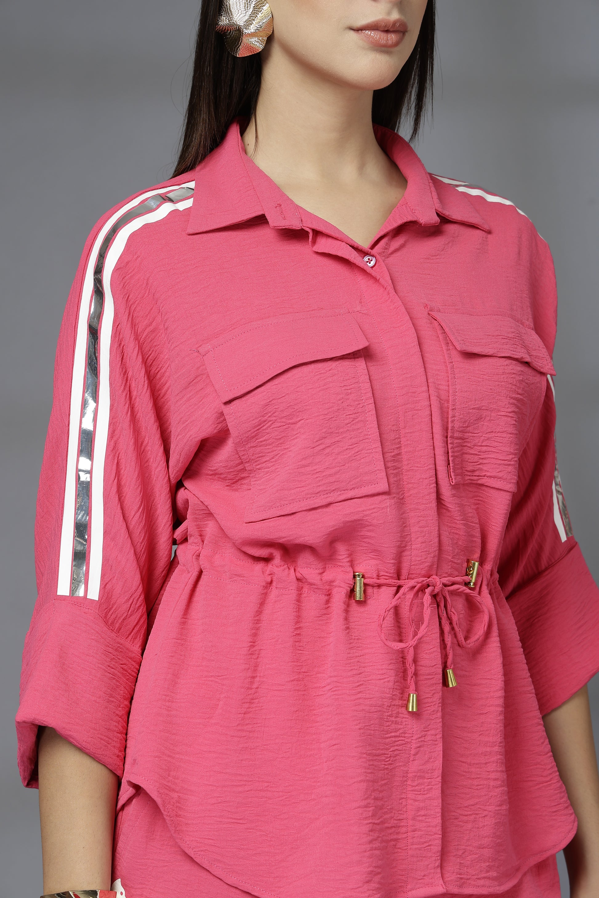 Pink outfit with white stripes on sleeves against a gray background