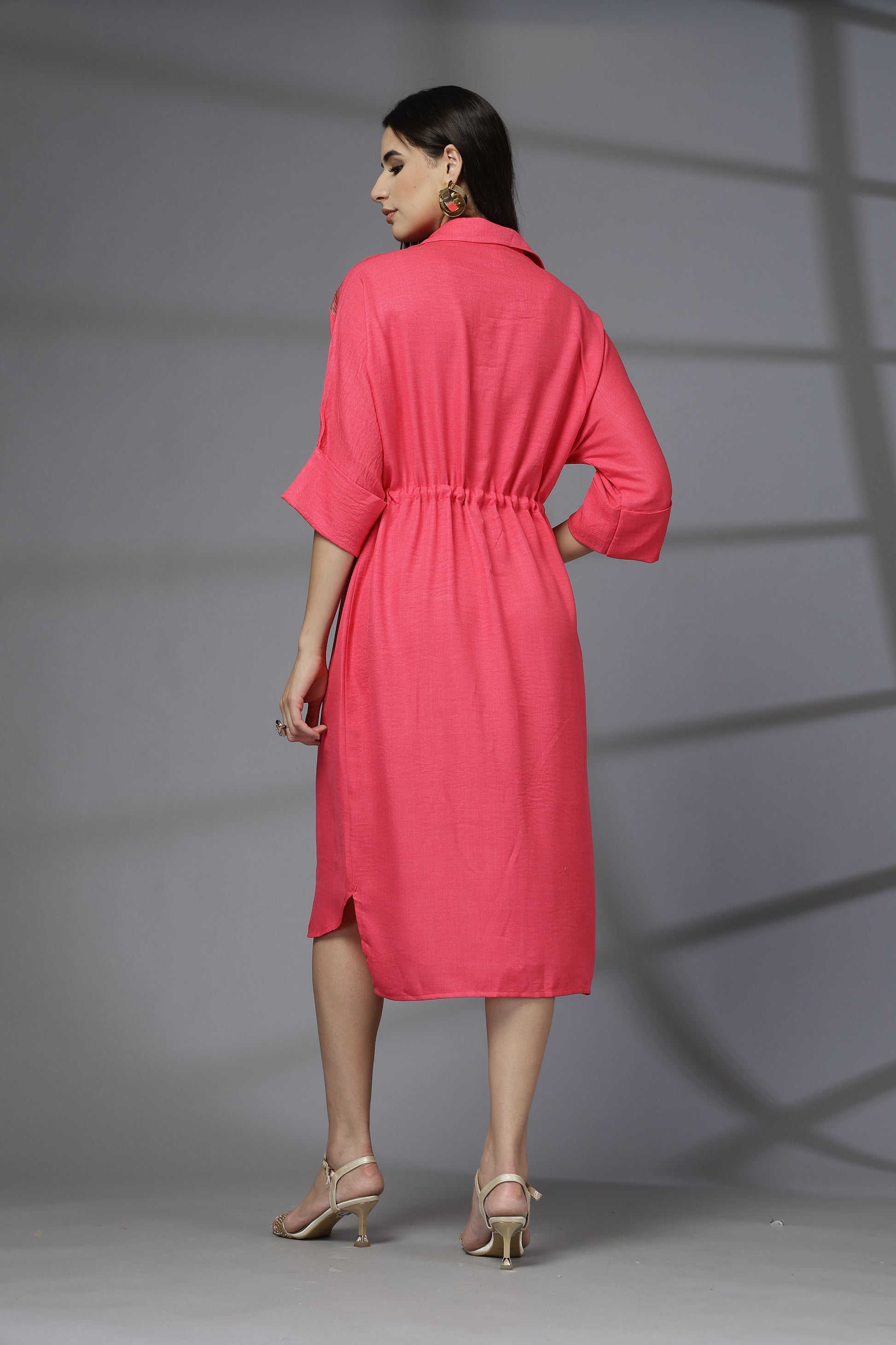 Woman wearing a pink dress against a gray background