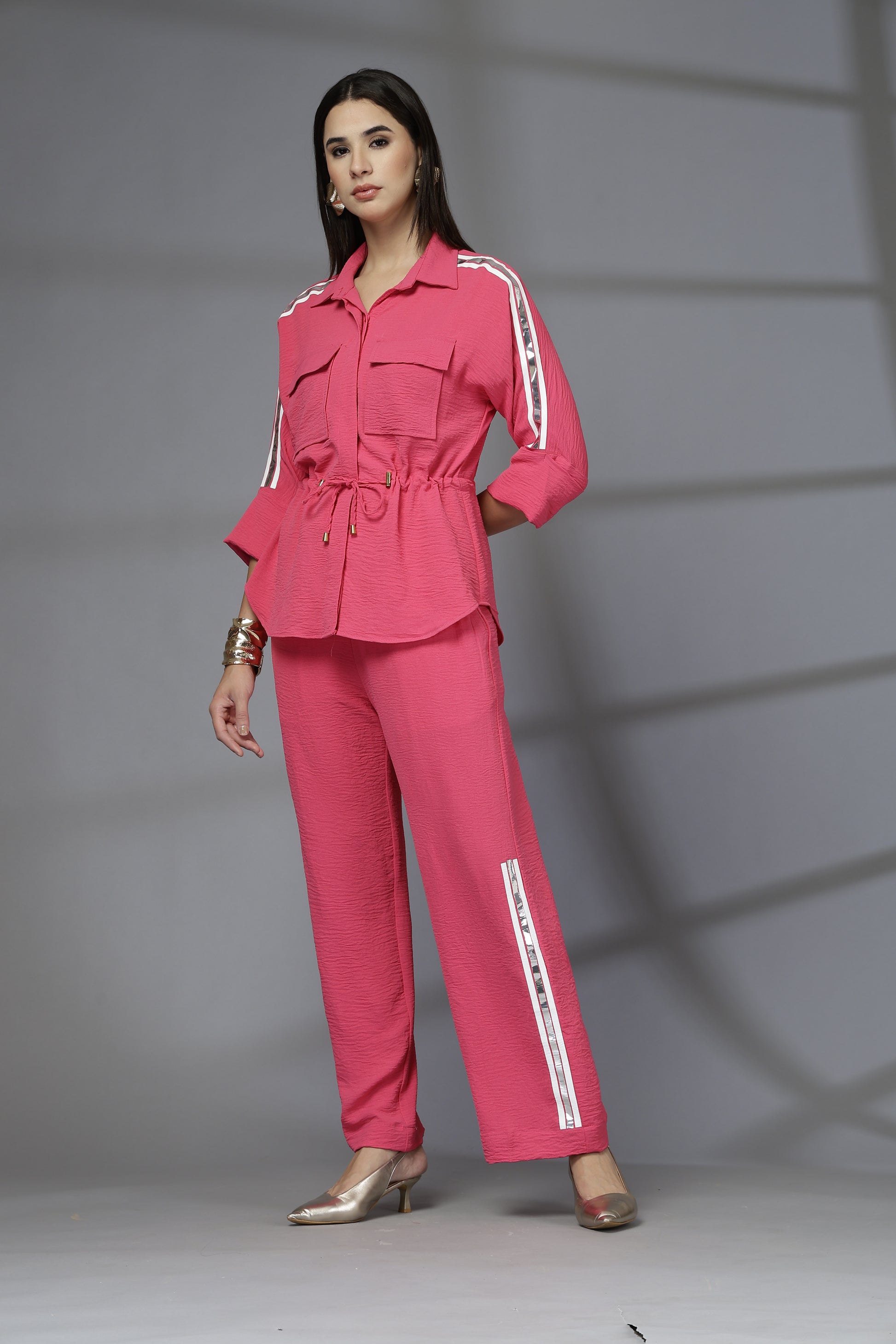 Woman wearing a pink outfit with white stripes on a gray background