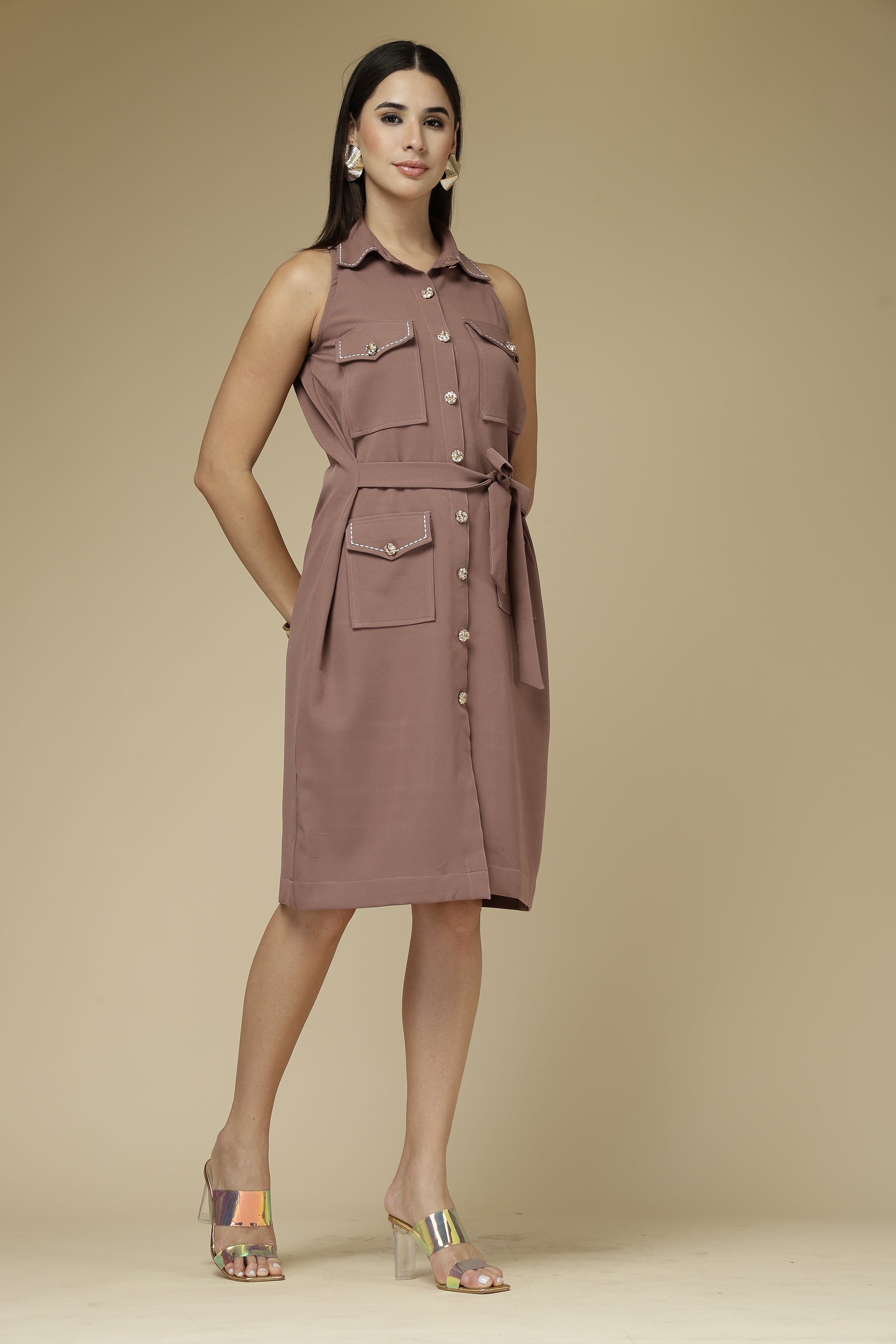 Woman wearing a sleeveless, button-up dress against a beige background