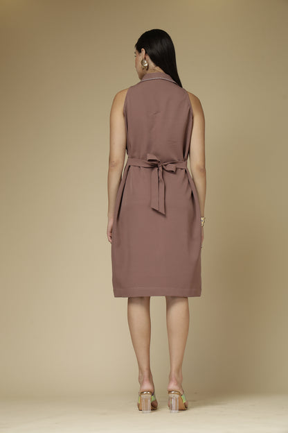 Woman wearing a brown sleeveless dress with a belt on a beige background