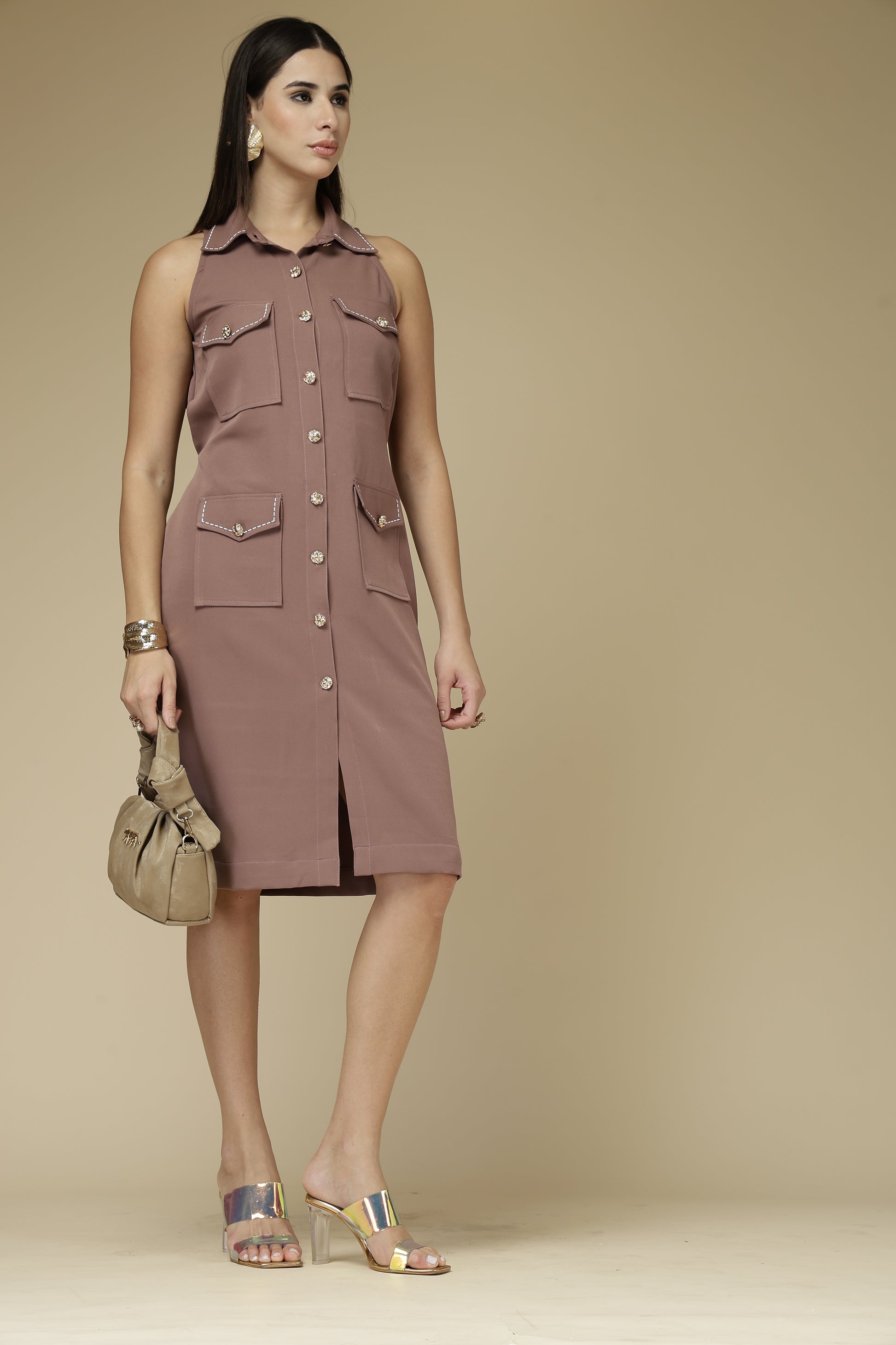 Woman wearing a brown dress with button details against a beige background