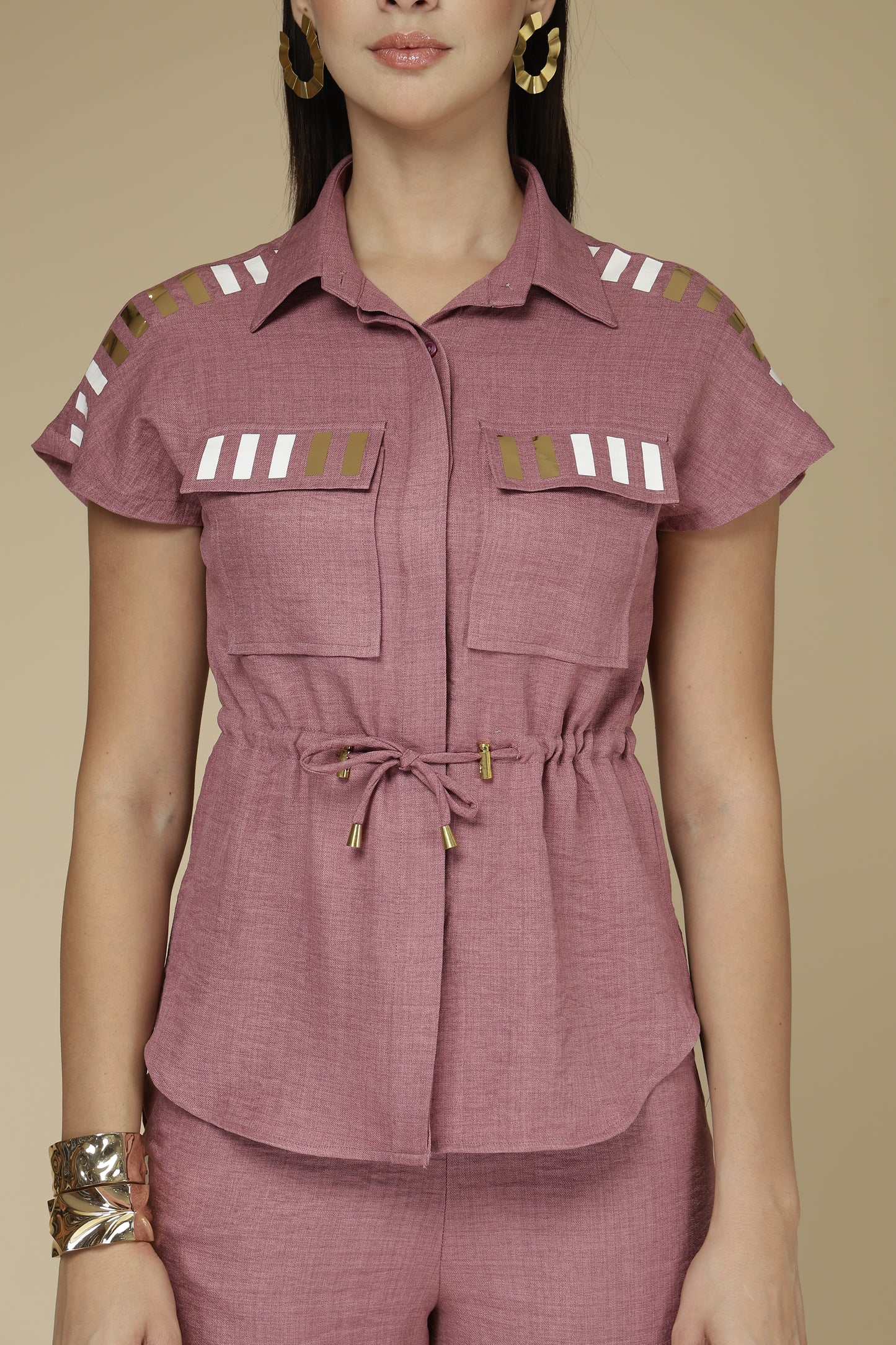 Woman wearing a mauve top with shoulder designs on a beige background
