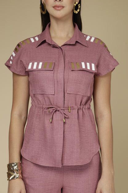 Woman wearing a mauve top with shoulder designs on a beige background