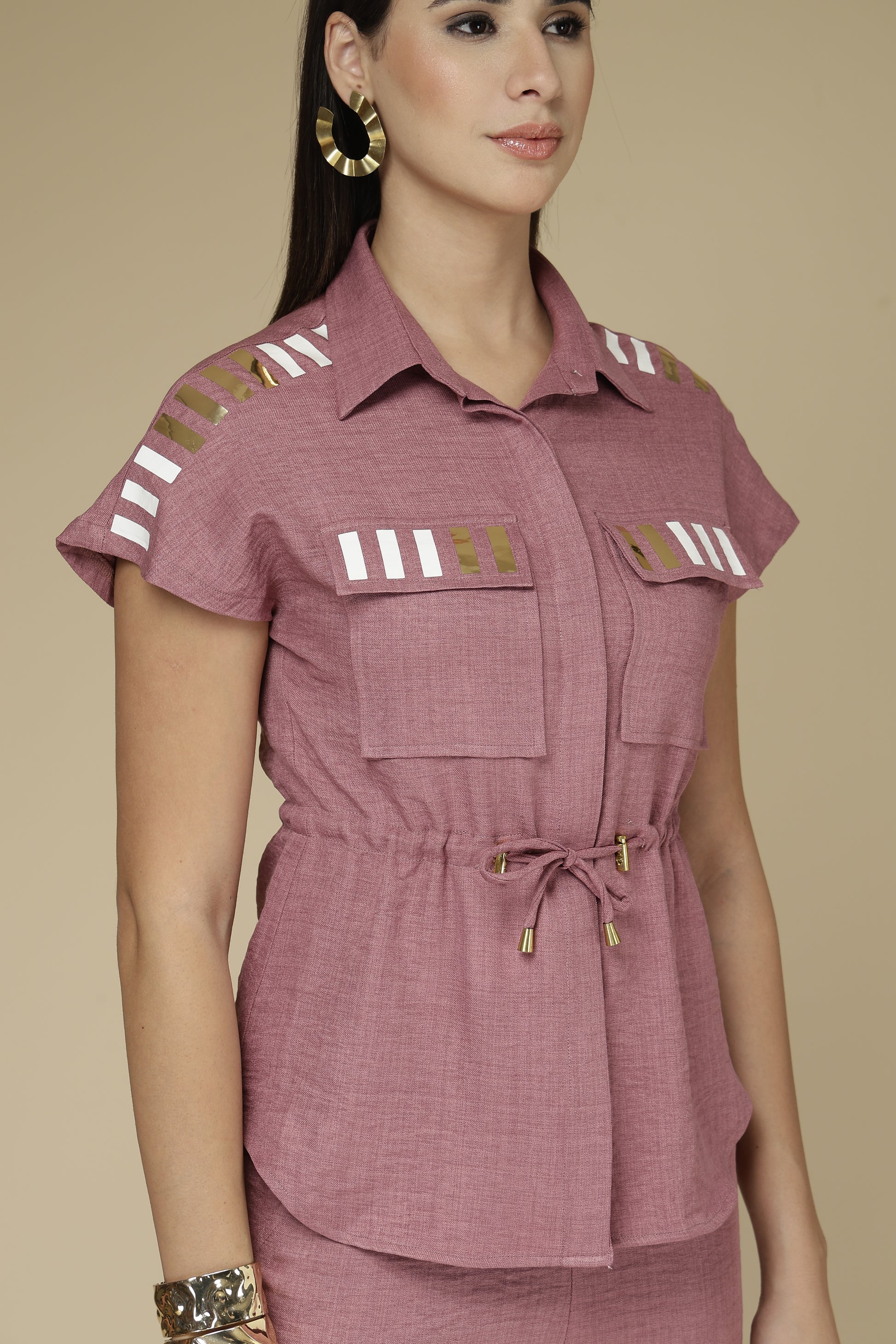 Woman wearing a mauve outfit with decorative elements on a beige background