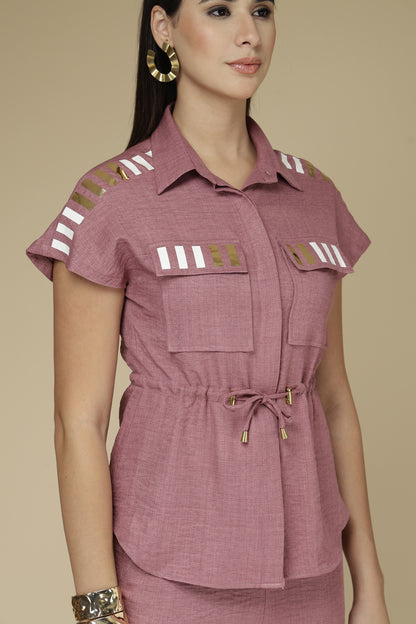 Woman wearing a mauve outfit with decorative elements on a beige background