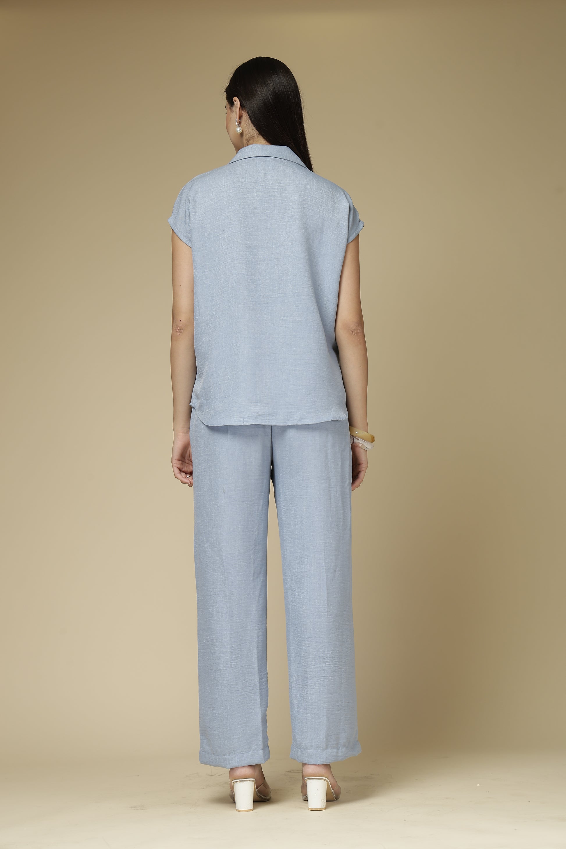 Woman wearing a light blue outfit against a beige background