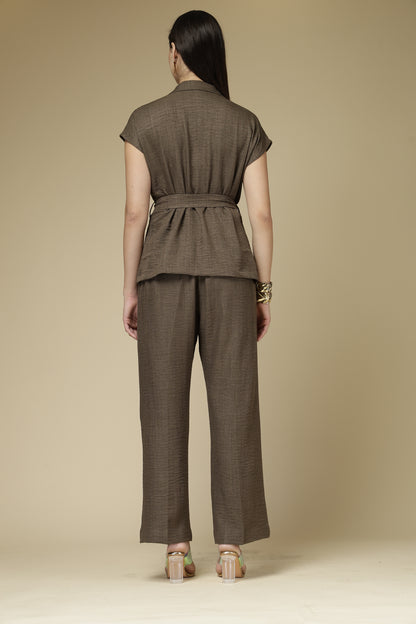 Woman wearing a brown outfit with a belt against a beige background
